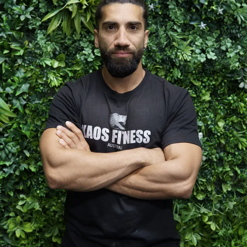 Kaos Fitness member in front of the plant wall