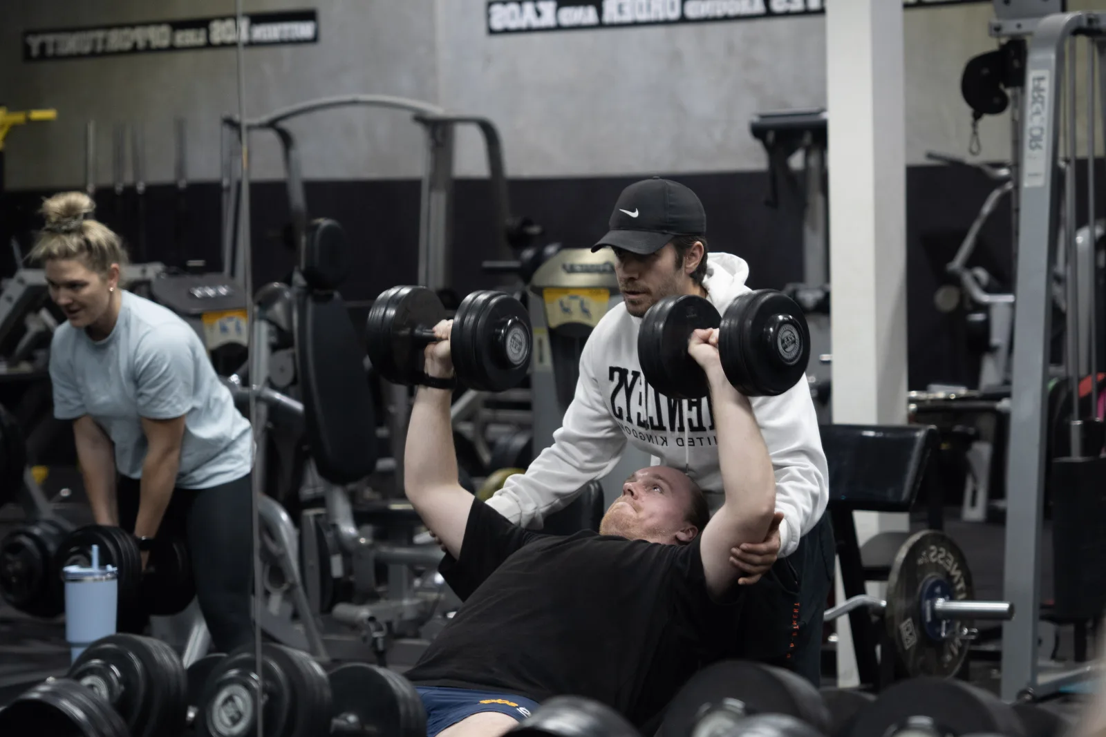 Kaos Fitness coach spotting a member during a dumbbell bench press